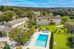 A stone house with a swimming pool, surrounded by a well-maintained lawn and trees. - Villa Le Vieux Mas by Villa Plus (Aubussargues)