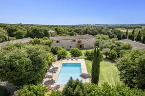 A stone villa with a swimming pool surrounded by lush greenery and a clear sky. - Villa Le Vieux Mas by Villa Plus (Aubussargues)