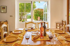 Une table à manger dressée avec des assiettes, des verres et des bouteilles, donnant sur un paysage verdoyant.