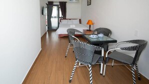 A hotel room with a bed, a desk with a lamp, and two patterned chairs. - Seimy Homestay (Da Nang)