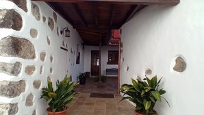 Un bâtiment aux murs de pierre, doté d’une entrée carrelée et d’un escalier en bois.