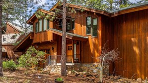 A two-story wooden cabin with a stone foundation, a balcony, and a stone wall. - Northstar Home w/Rec Center Access (Truckee)
