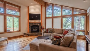 A spacious living room with a fireplace, large windows, and a cozy seating area. - Northstar Home w/Rec Center Access (Truckee)