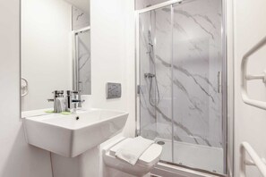 A modern bathroom with a white sink, a mirror, and a glass-enclosed shower. - Characterful 1 Bed Apartment in Central Sheffield (Sheffield)