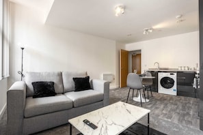 A modern living room with a grey sofa, a marble coffee table, and a washing machine in the background. - Characterful 1 Bed Apartment in Central Sheffield (Sheffield)