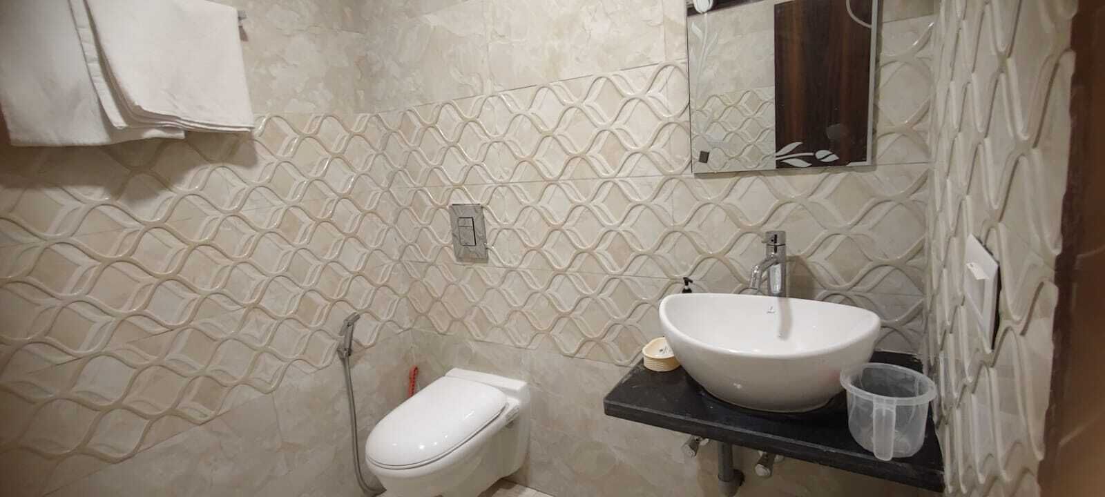 A bathroom with a toilet, a sink, and a mirror.