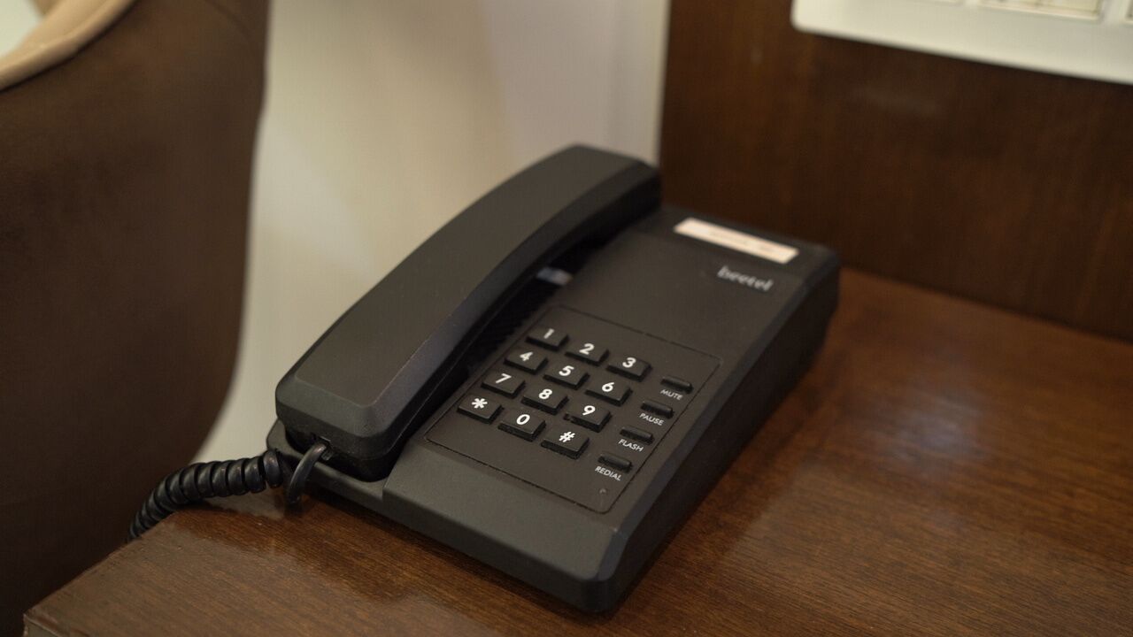 Egy fekete telefon egy fa asztalon.