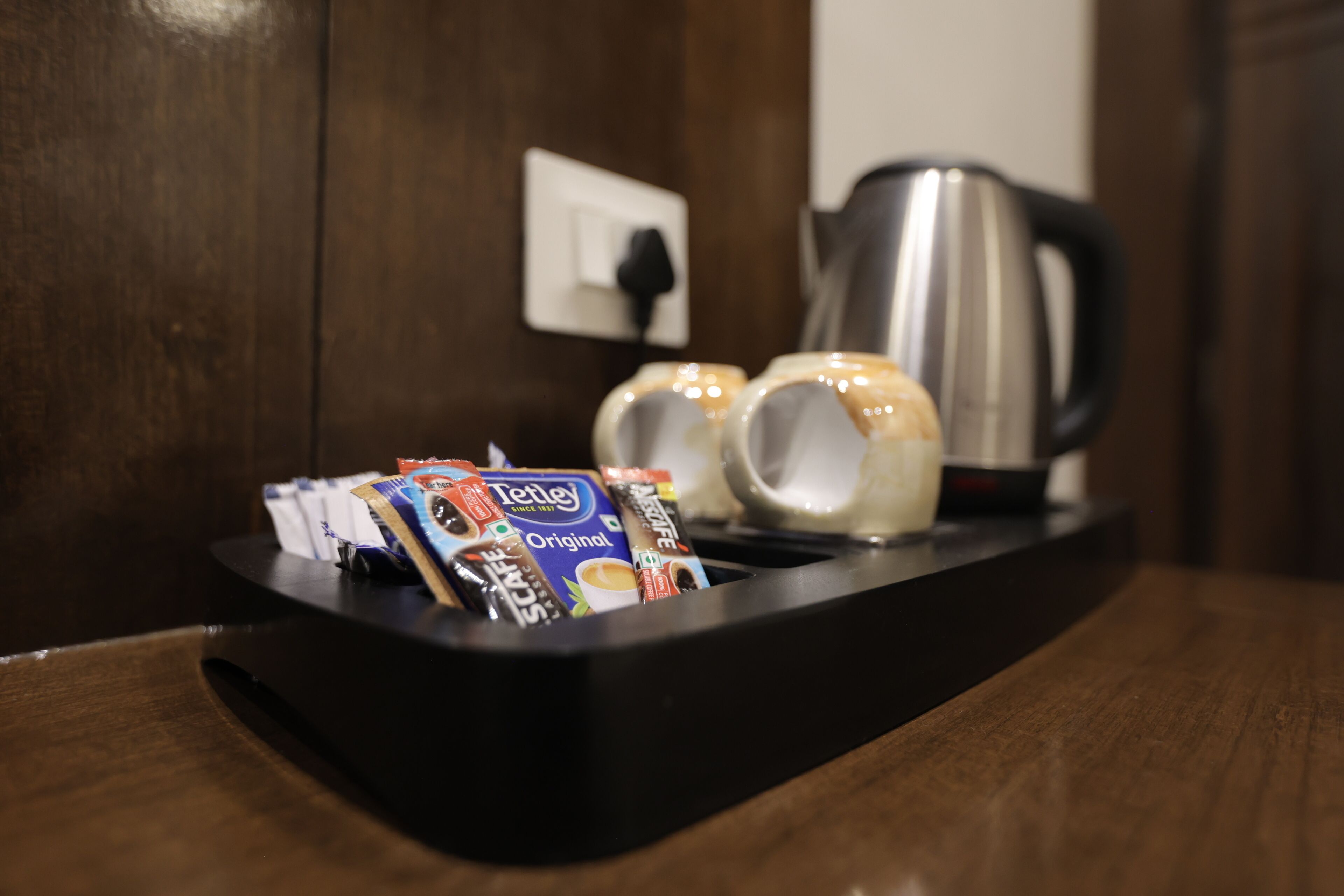 Una cafetera y una bandeja con cápsulas de café sobre una mesa de madera.