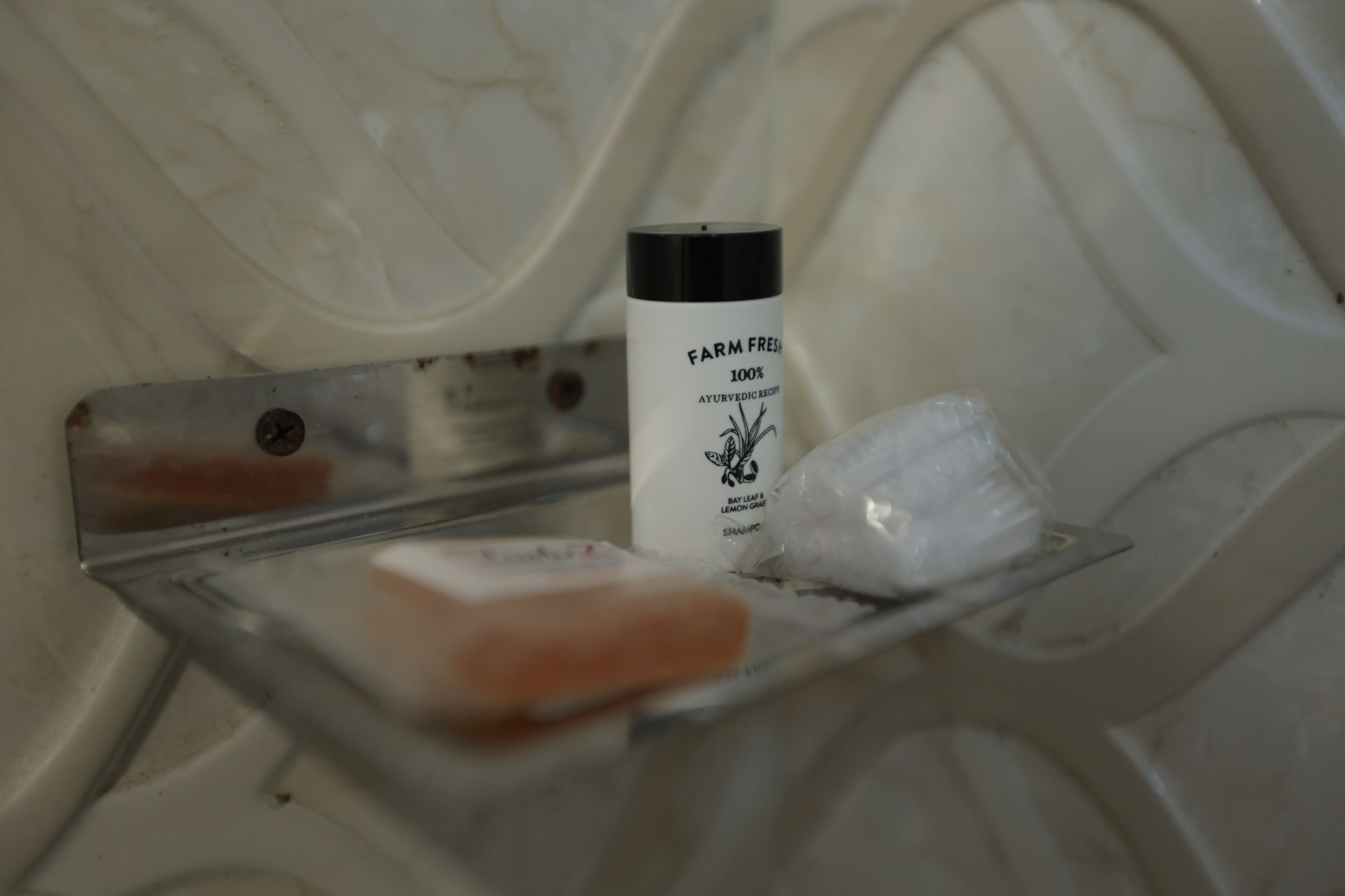 A bathroom with a white bathtub, a bottle of Farm Fresh 100% Ayurvedic Recipe Bay Leaf & Lemon Cream Shampoo, and a bar of soap.