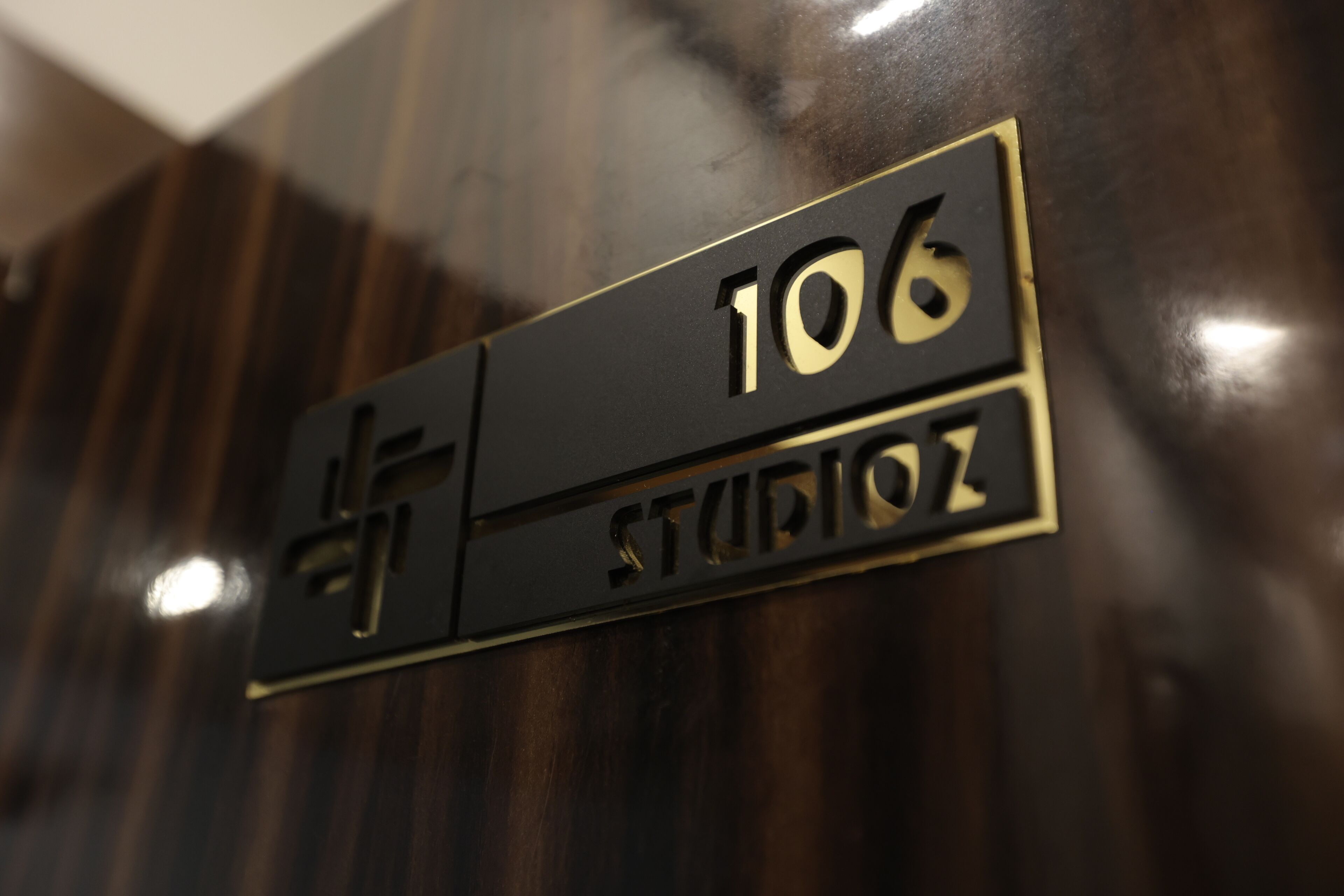 A sign with the number 106 and the word "STUDIOZ" on a dark wooden wall.