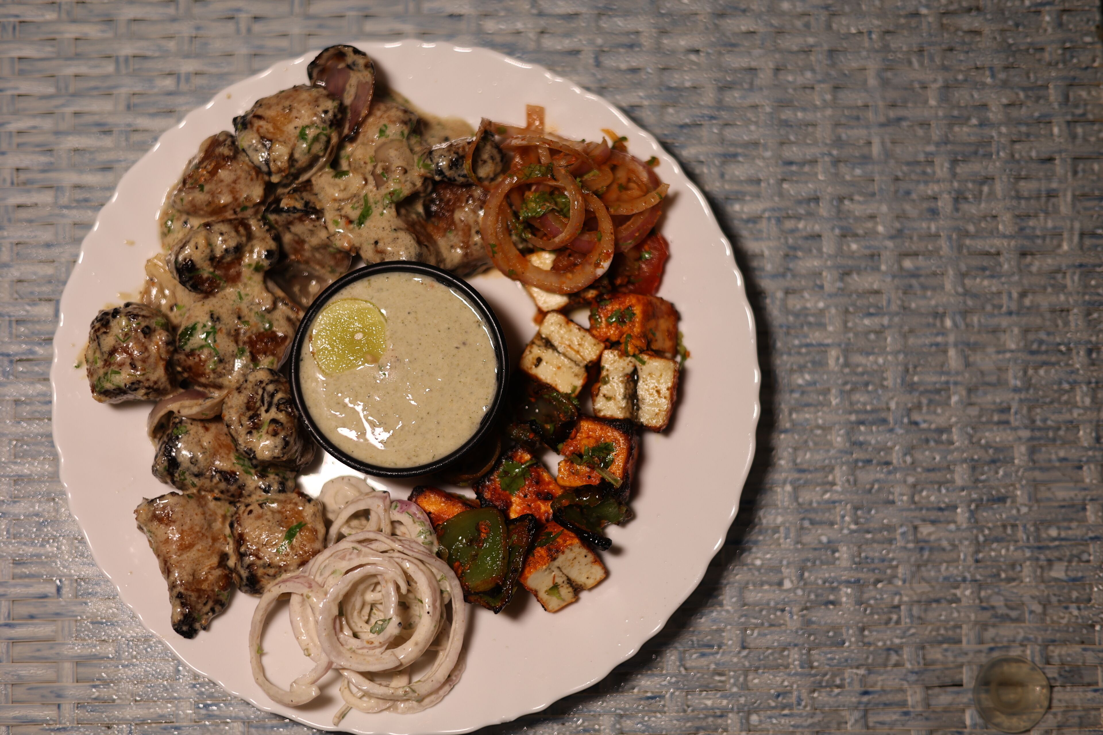 A plate of grilled chicken, vegetables, and a side of sauce.