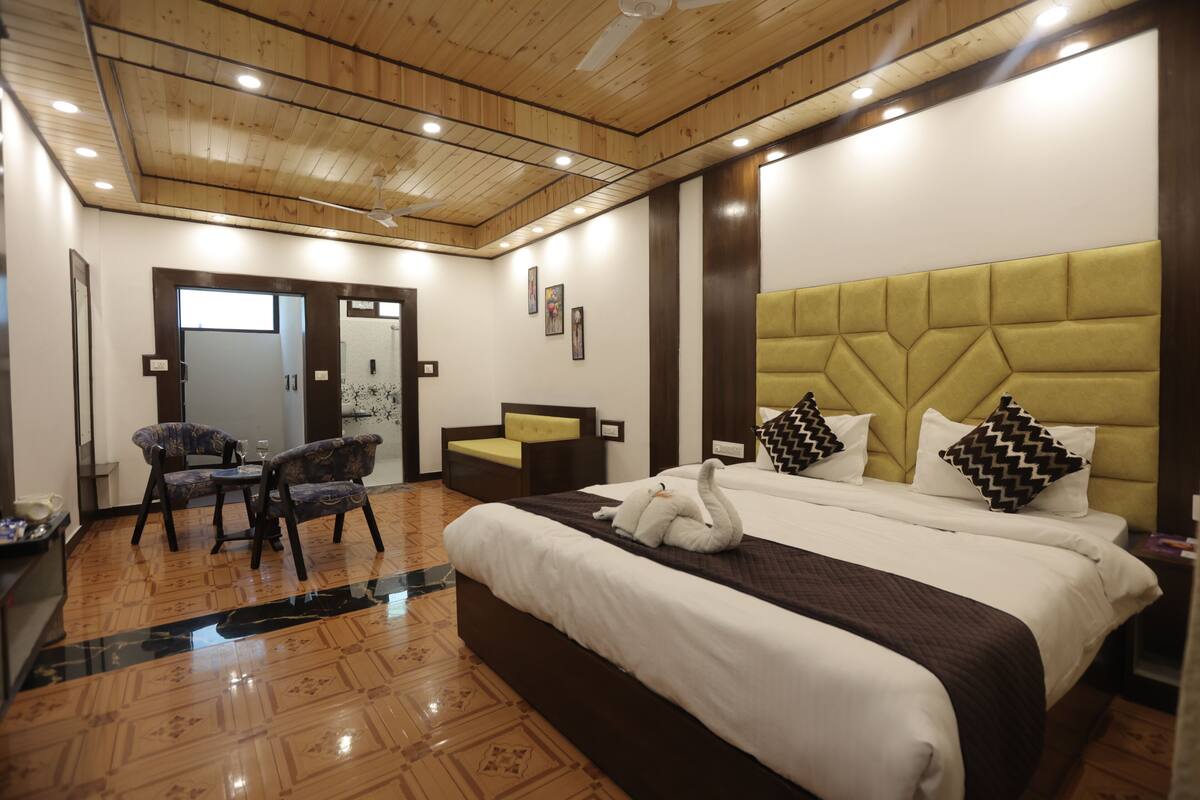 A hotel room with a large bed, a wooden ceiling, and a seating area with chairs.