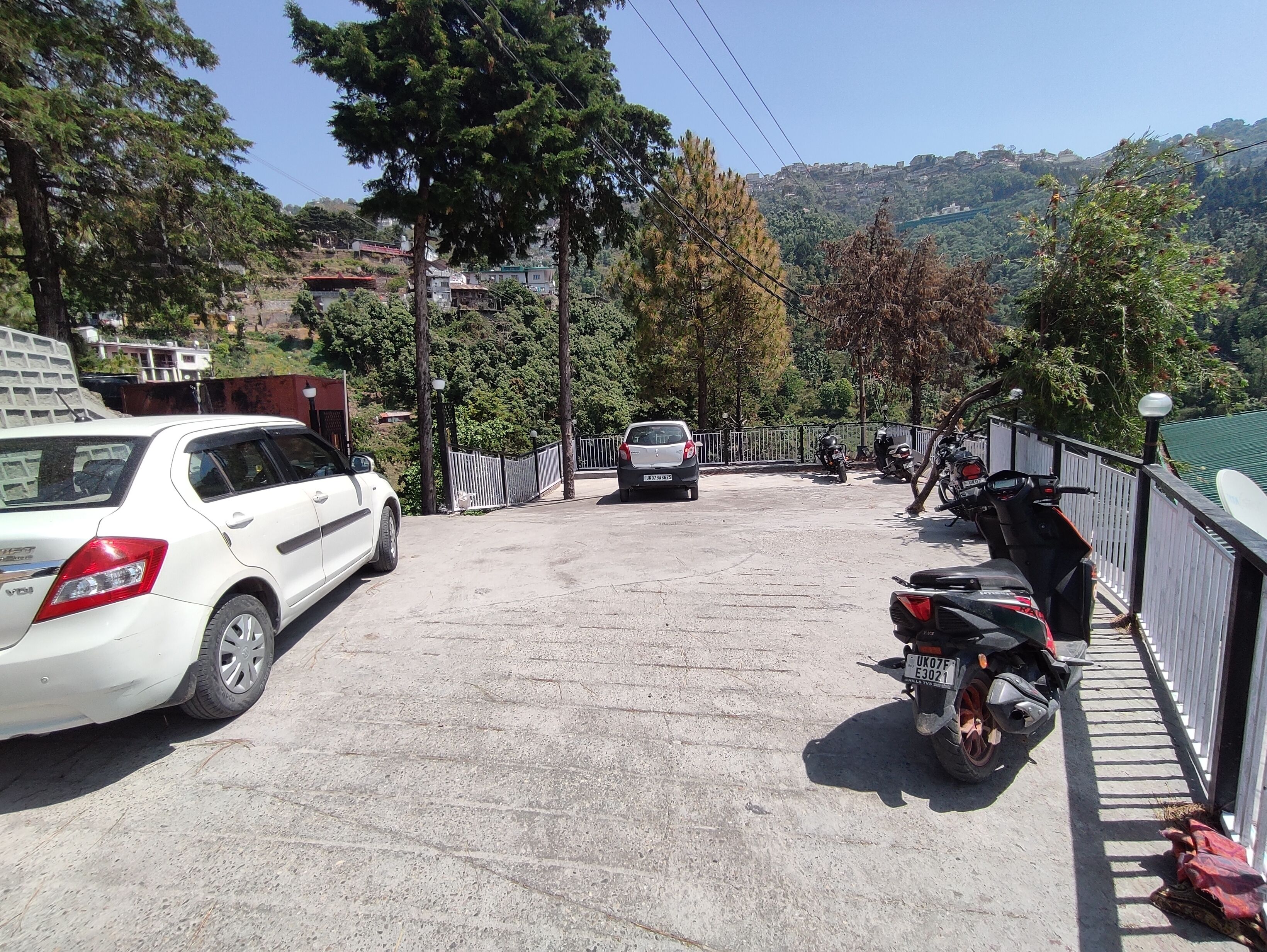 A parking area with a white car and several motorcycles.