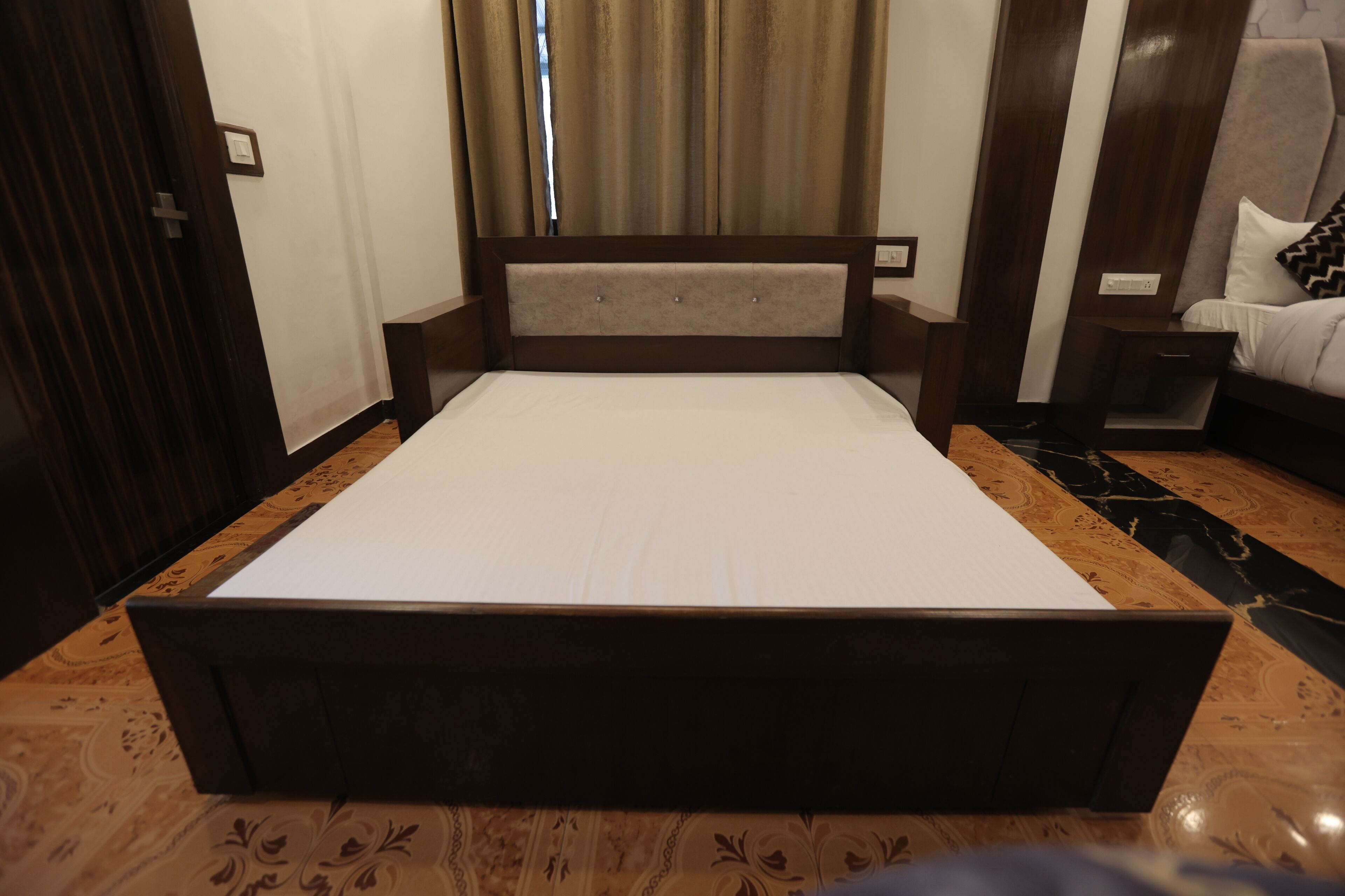 Una camera d'albergo con un letto grande, una testiera in legno, un comodino e un tavolino da notte.
