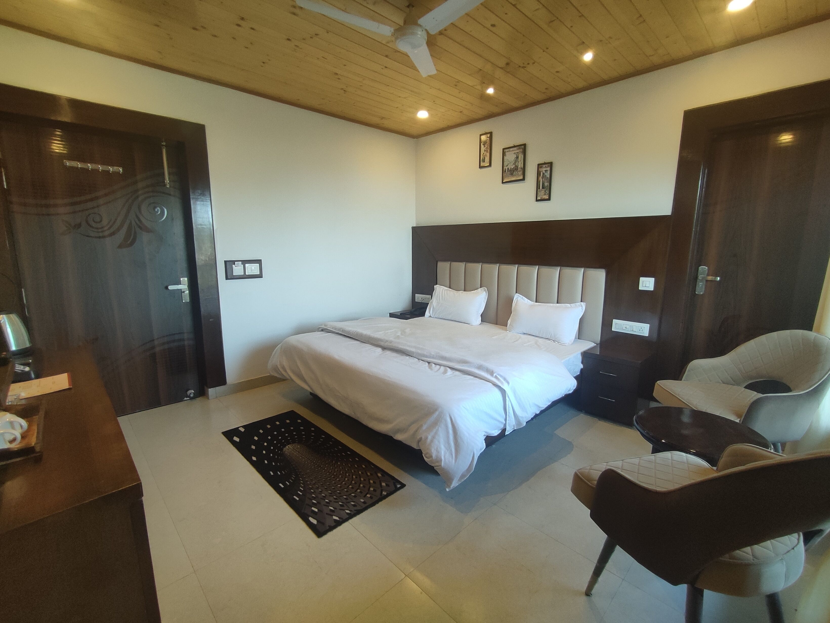 A bedroom with a large bed, bedside tables, a chair, and a decorative rug.