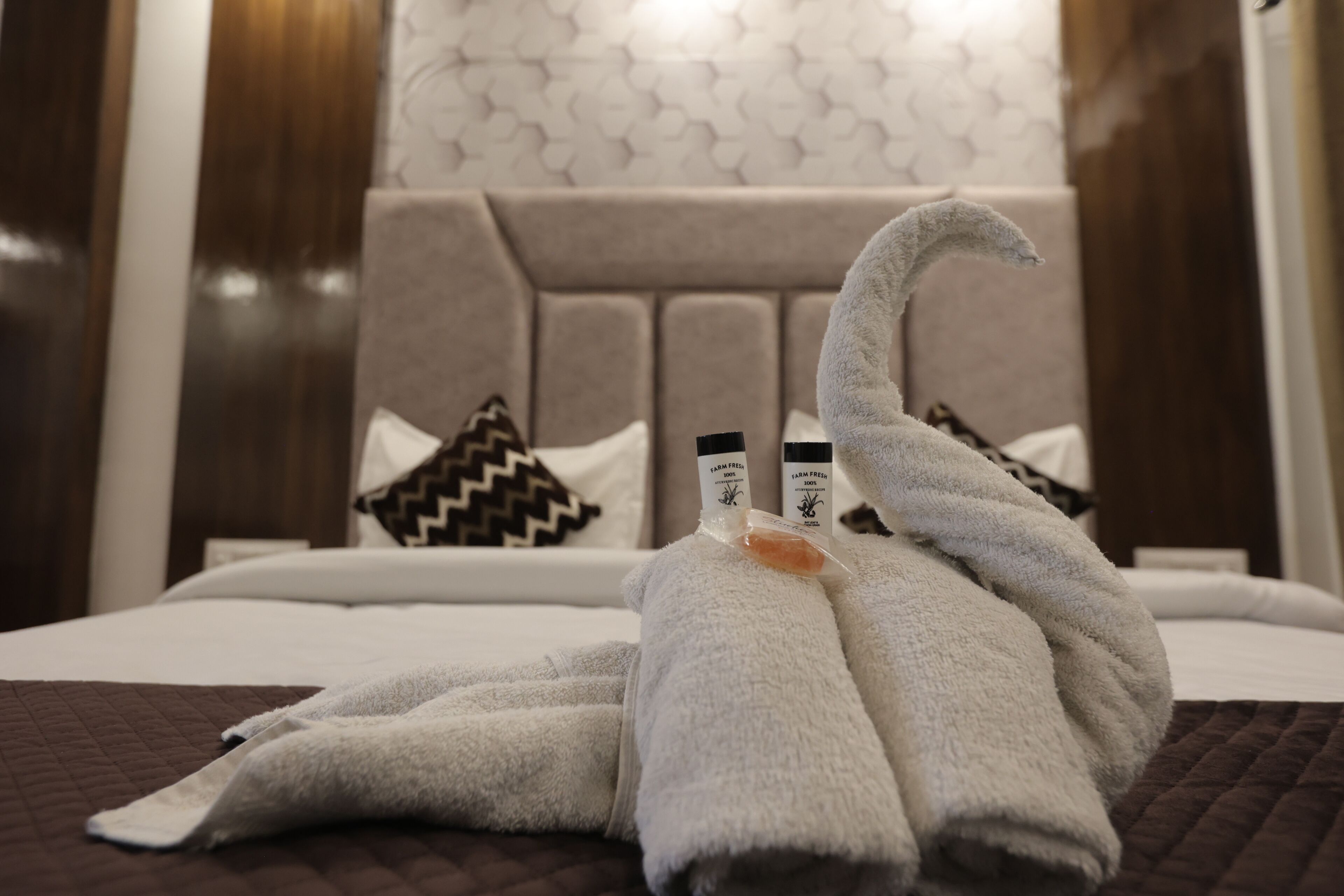 A neatly made bed with a headboard, pillows, and a towel arranged in a swan shape.