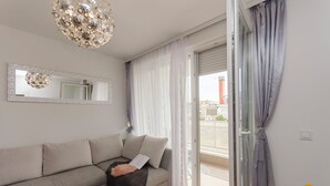 A modern living room with a grey sofa, a decorative mirror, and a large window with curtains. - Apartment L and I (Sibenik)