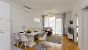A modern living room with a dining area, a sofa, a TV, and a chandelier. - Apartment L and I (Sibenik)