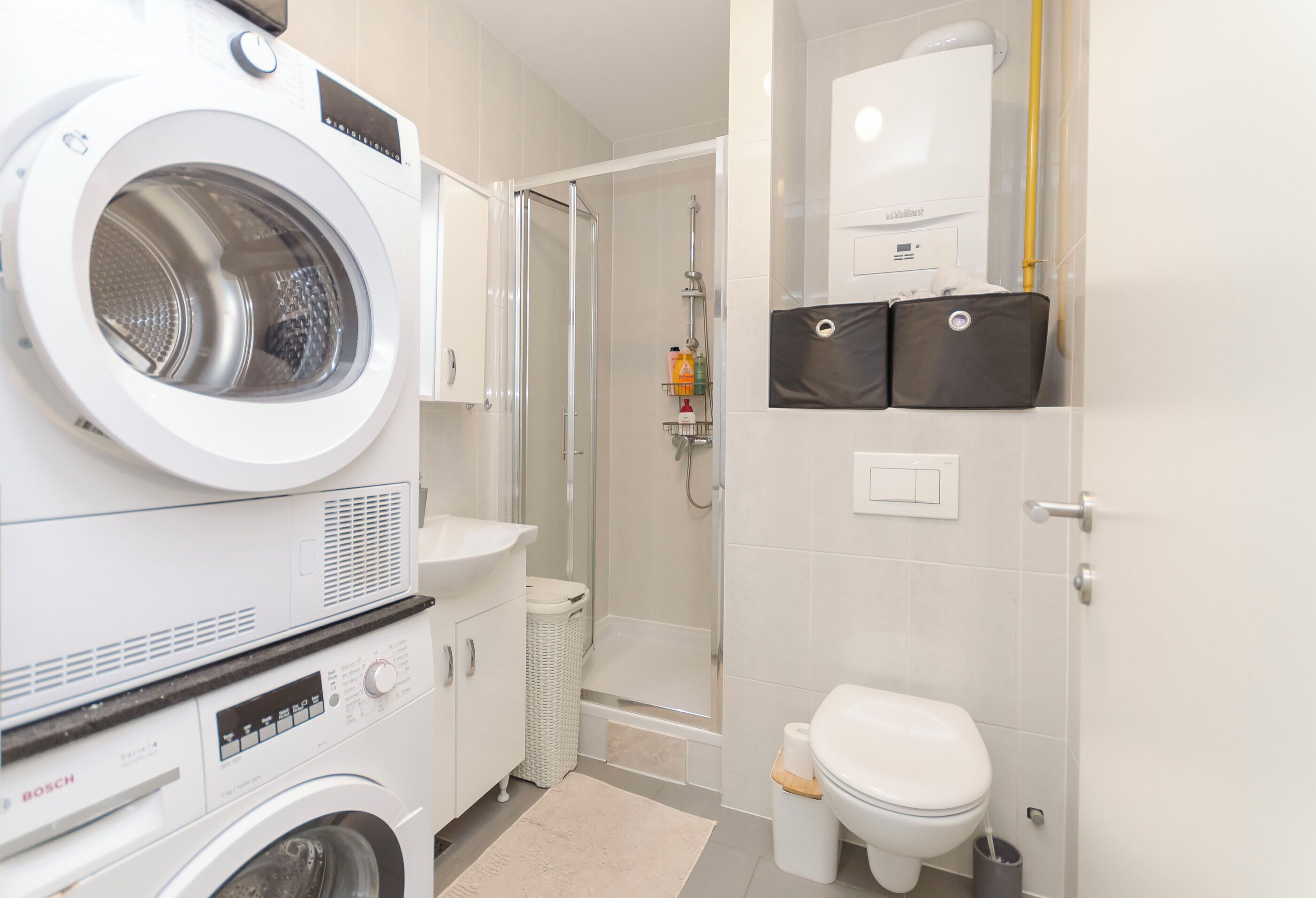 A compact hotel bathroom with a washing machine, a bathtub, and a toilet.