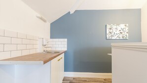A compact kitchen with white cabinets, a wooden countertop, and a blue accent wall. - Stunning 5-bed Maisonette in Bristol (Bristol)