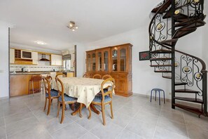 Enjoy meals with family and friends in this dining area, featuring a large table and matching chairs, adjacent to a well-equipped kitchen.