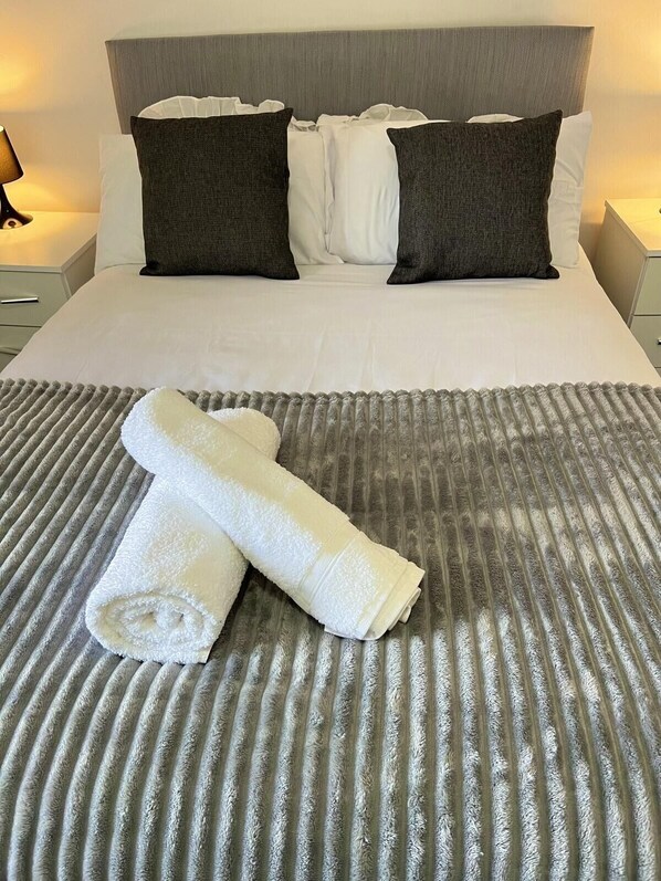 Restful retreat with a neatly made bed, featuring a striped bedspread and a grey headboard.