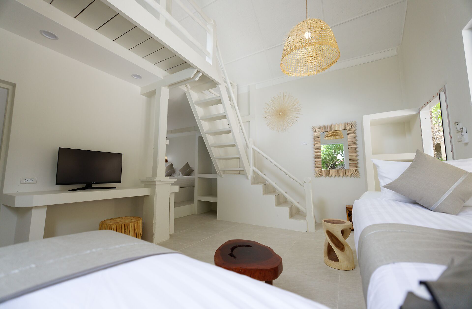 A modern bedroom with a TV, a staircase, a bed, and a hanging light fixture.