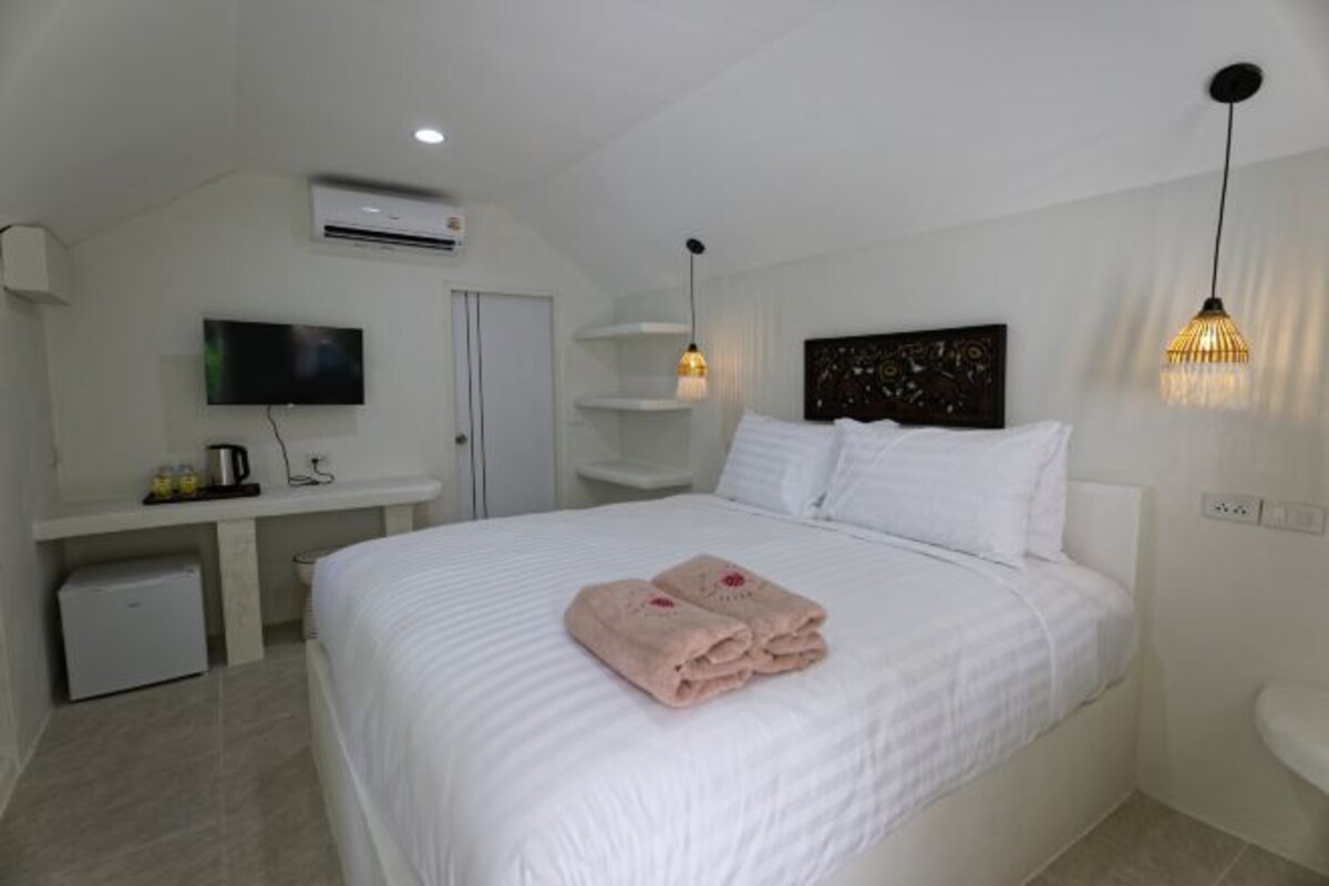 A hotel room with a bed, a TV, a desk with a computer, and a bathroom.