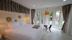 A spacious bedroom with a large bed, a chair, and a view of the outdoors through large windows. - Blue Turtle Hotel Samui (Koh Samui)