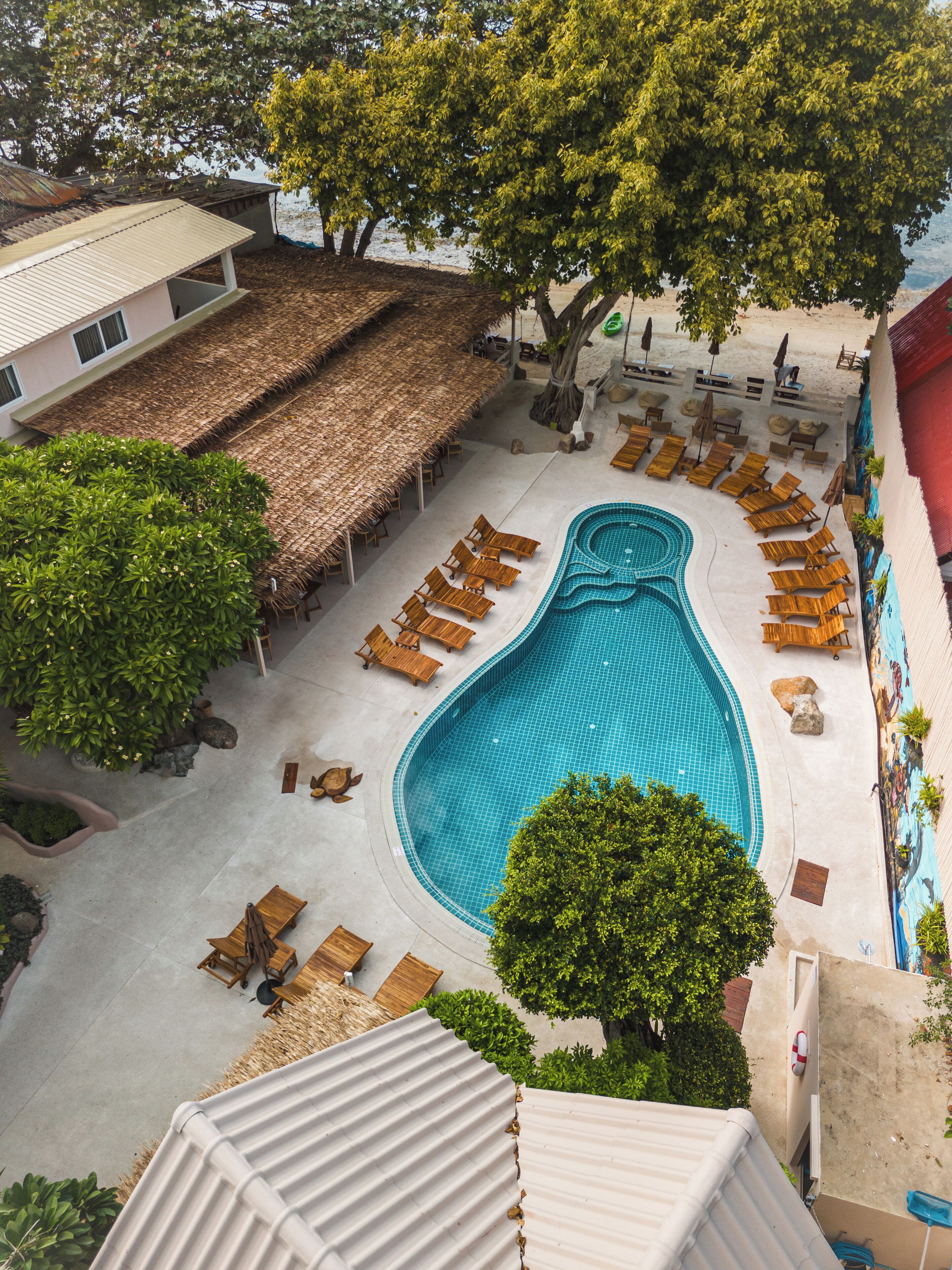 A swimming pool with lounge chairs and a thatched roof structure.