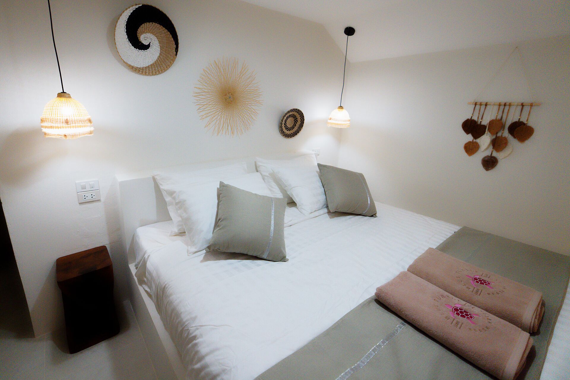 A neatly made bed with pillows, a bedside table, and a wall-mounted light fixture.