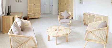 Un amplio salón con mobiliario de mimbre, incluyendo sofás y sillones, y una mesa de centro redonda.