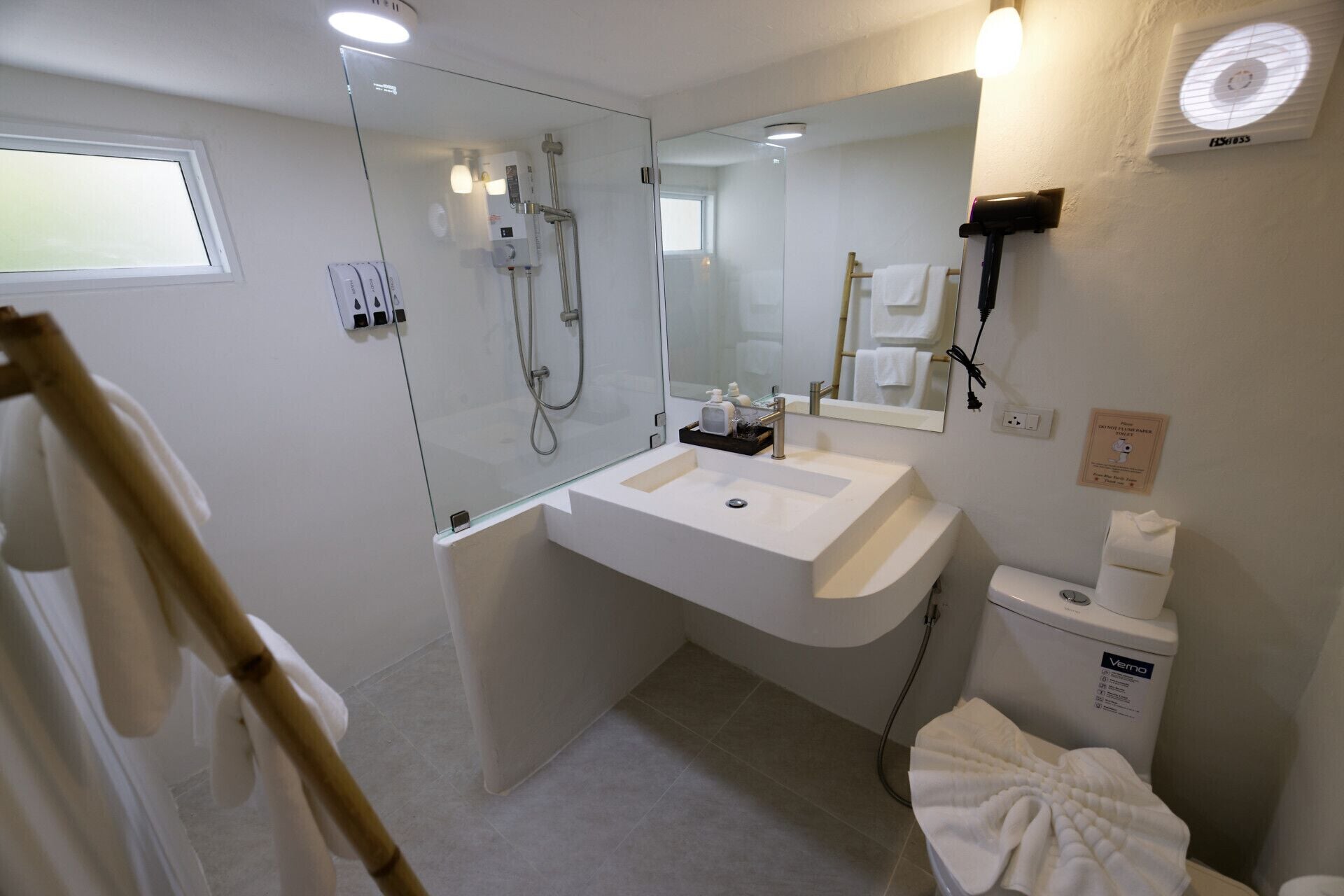 A modern bathroom with a glass shower enclosure, a white sink, and a toilet.
