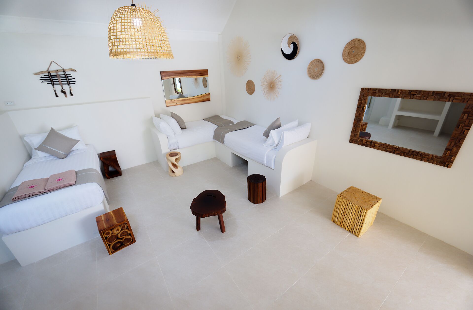 A modern, minimalist bedroom with a white sofa, a smaller bed, and a large mirror.