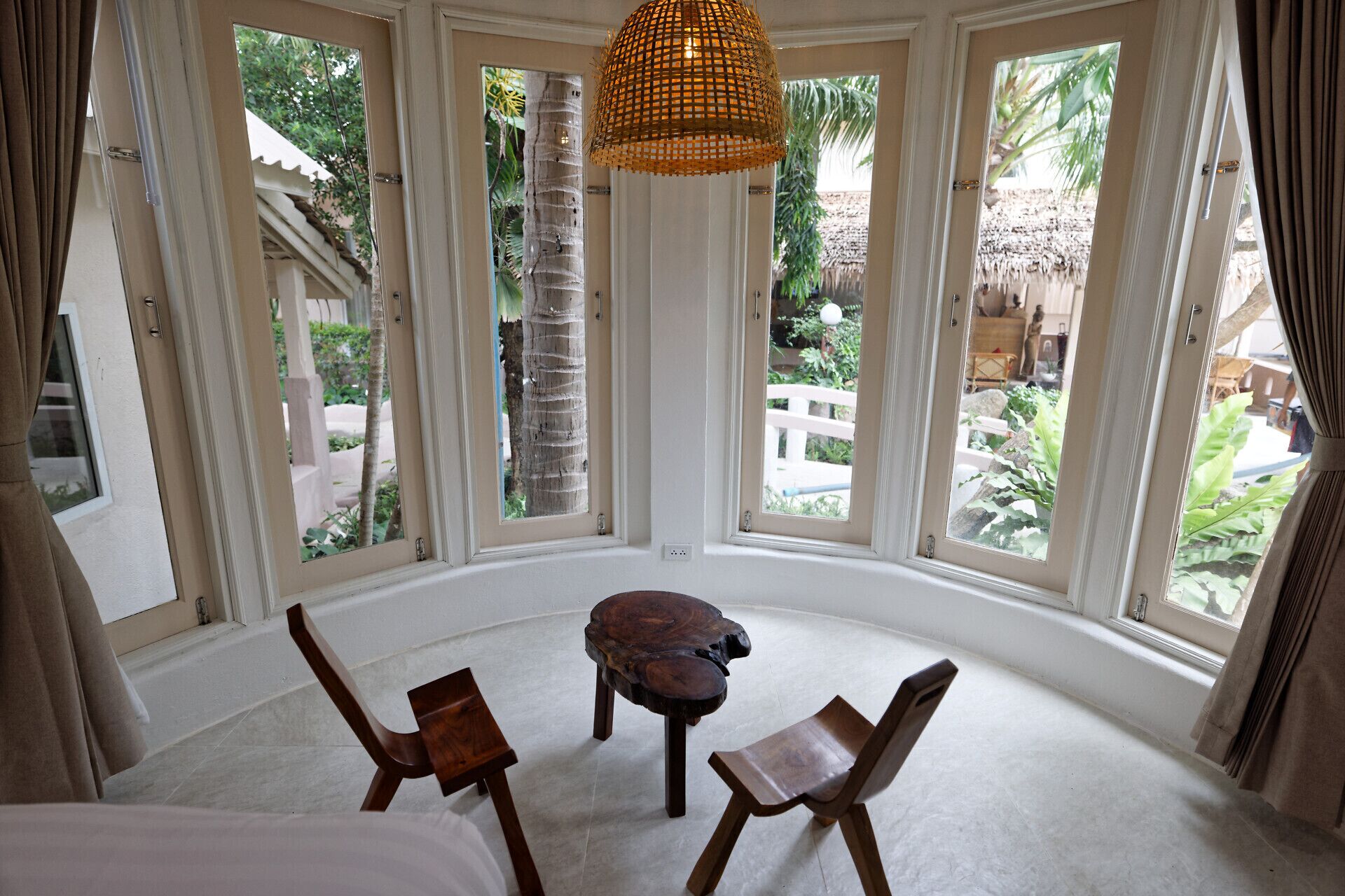 A room with a large bay window, a woven pendant light, and two wooden chairs.