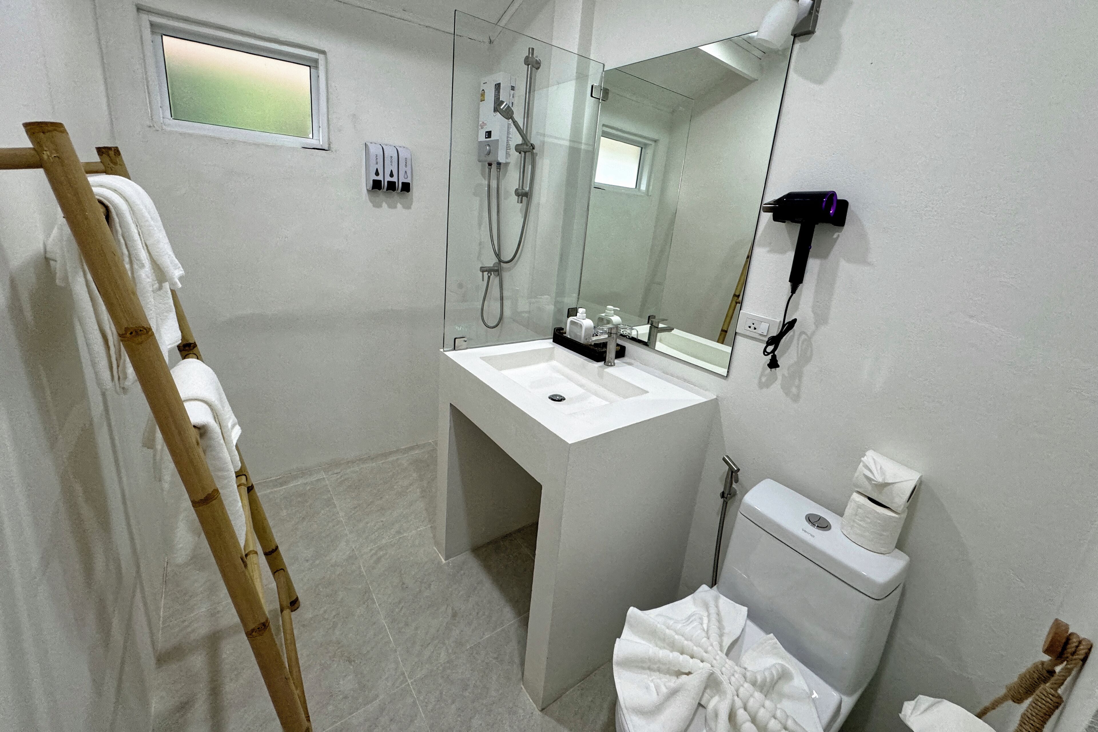 A bathroom with a white sink, a glass shower enclosure, a toilet, and a towel rack.