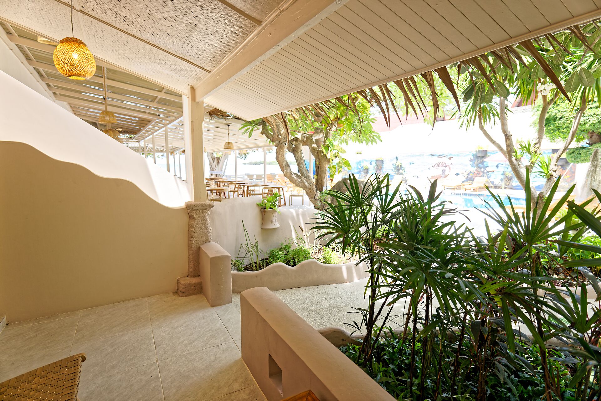A covered outdoor area with a pool, potted plants, and a seating area.