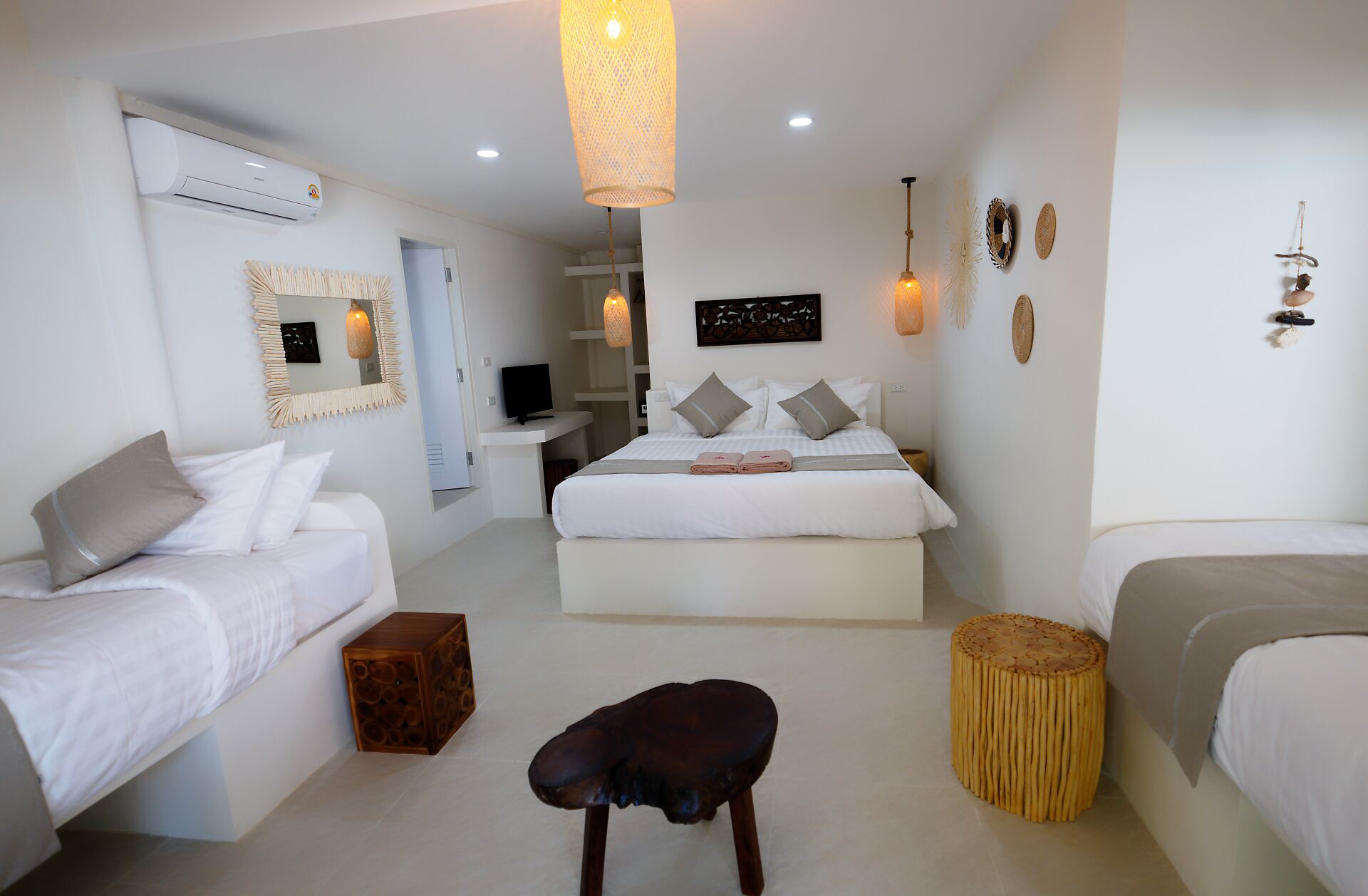 A hotel room with two beds, a TV, a mirror, and a hanging light fixture.