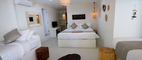 A hotel room with two beds, a TV, a mirror, and a hanging light fixture.