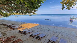 A beach with sun loungers and a calm sea. - Blue Turtle Hotel Samui (Koh Samui)