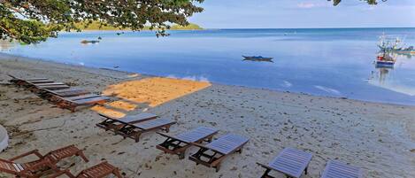 A beach with sun loungers and a calm sea.