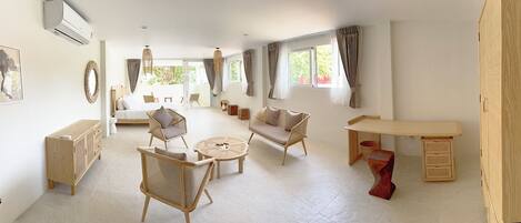 A spacious room with a sofa, two wicker chairs, a small round table, and a wooden cabinet.