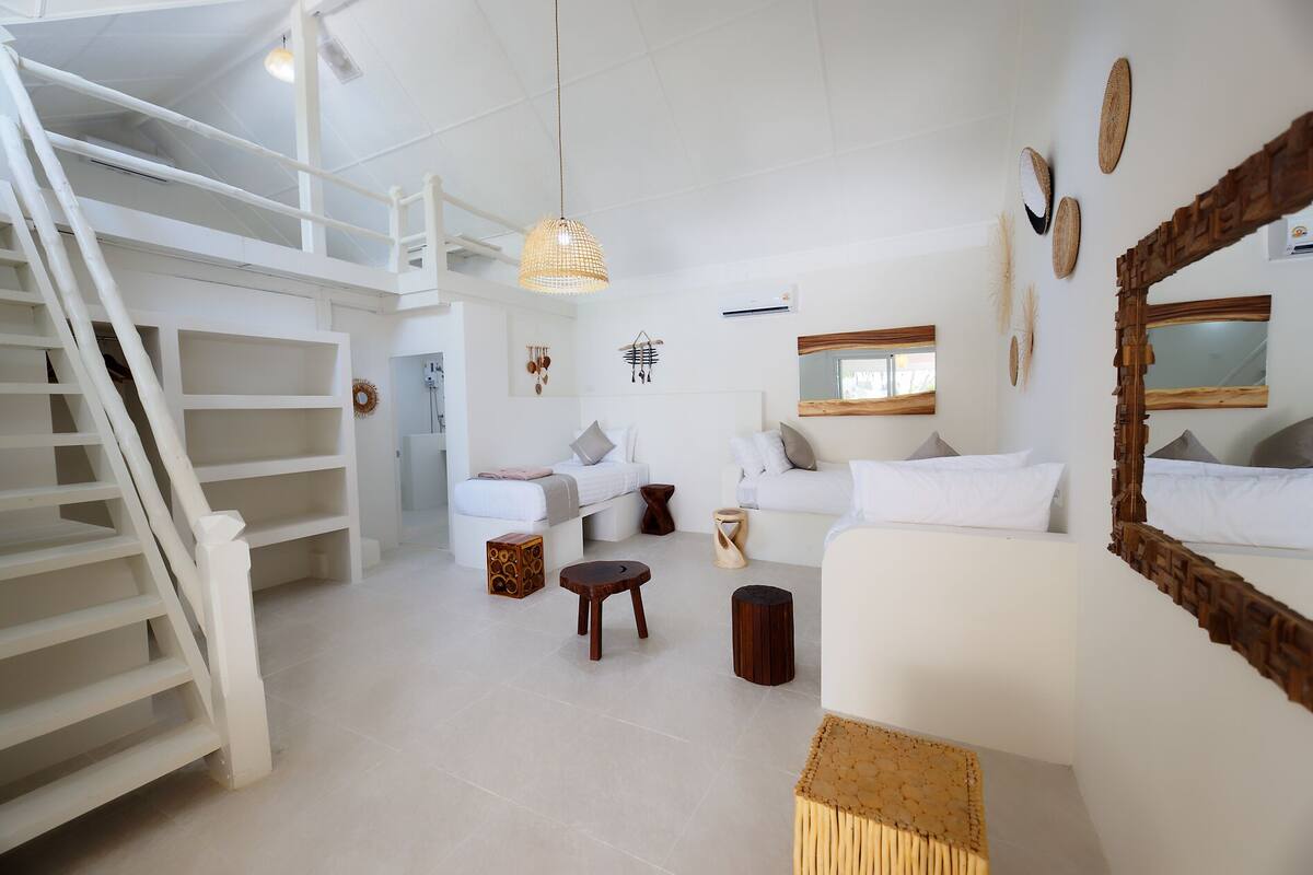 A spacious living area with a staircase, white furniture, and decorative wall art.