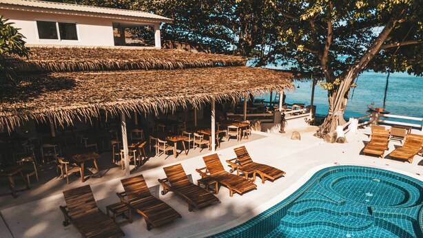 A poolside area with lounge chairs and a thatched-roof structure. - Blue Turtle Hotel Samui (Koh Samui)