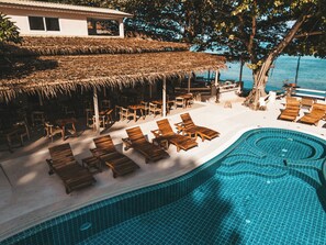 A poolside area with lounge chairs and a thatched-roof structure. - Blue Turtle Hotel Samui (Koh Samui)