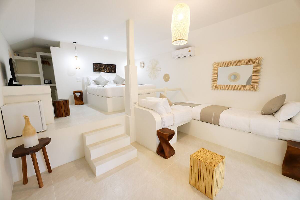 A modern, minimalist bedroom with a bed, a sofa, a wooden stool, and a small table.