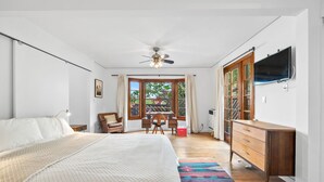 A bedroom with a bed, a desk, a chair, a TV, and a window with curtains. - The Robinson Tree House in Silver Lake (Los Angeles)