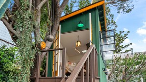 A treehouse with a wooden staircase, a green exterior, and a hanging light fixture. - The Robinson Tree House in Silver Lake (Los Angeles)