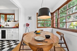 A kitchen with a dining table, chairs, and a large window with a view of trees.
