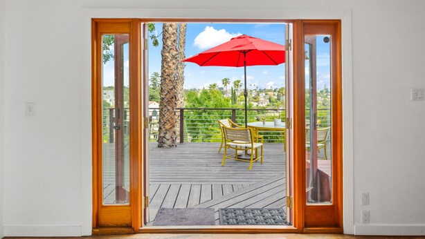 A view from a room to an outdoor deck with a red umbrella, a table, and chairs. - The Robinson Tree House in Silver Lake (Los Angeles)